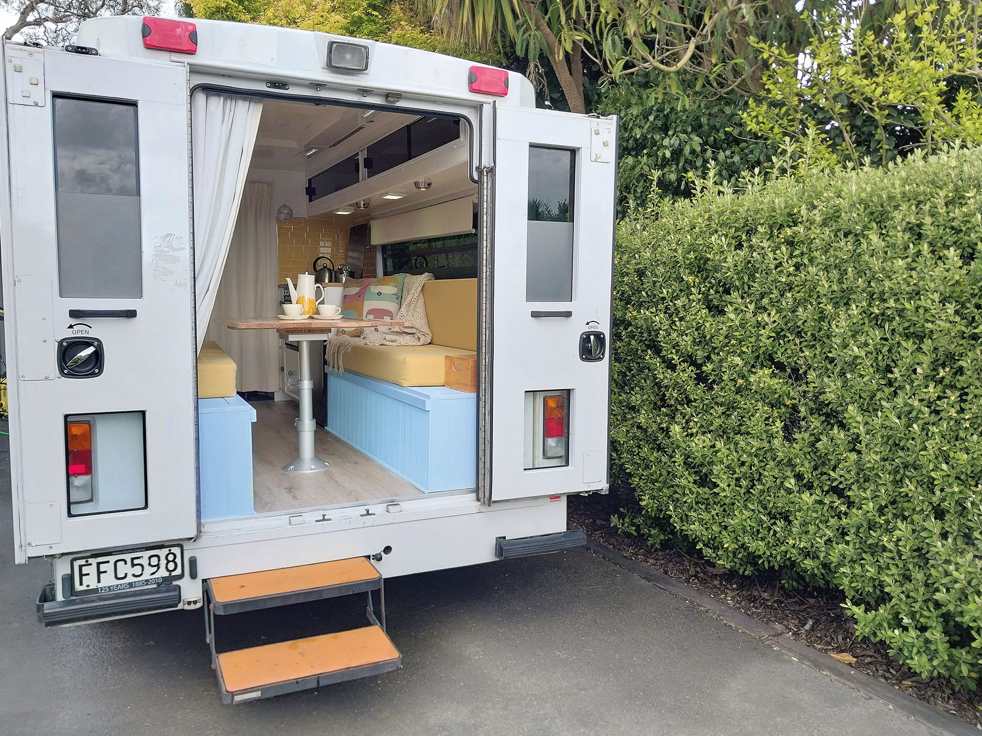 Ambulance motorhome renovation. Rear view with doors open. White and pale blue colour scheme