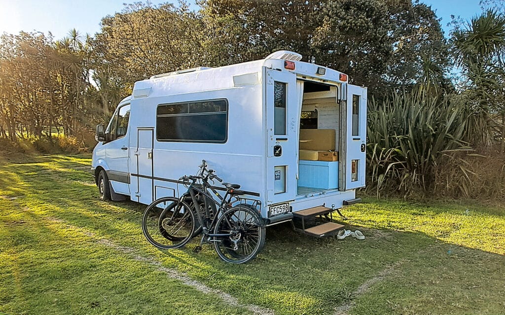 Ambulance motorhome renovation exterior side view with bicycles leaning against it